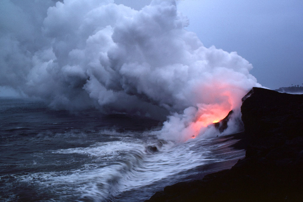 Glow of lava is reflected in steam plume at water’s edge east of Kupapa‘u Point, 10 February 1988, photo by T.J. Takahashi for United States Geological Survey HVO.